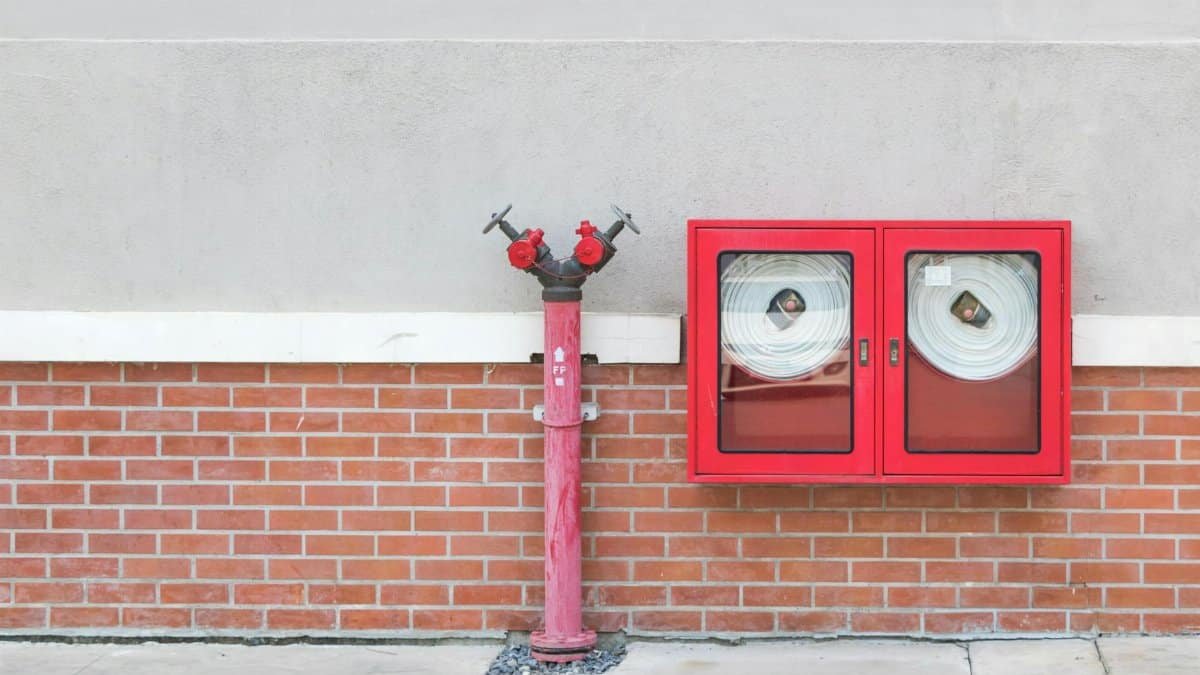 Outdoor fire hydrant and hoses against a brick wall, emphasizing fire safety.