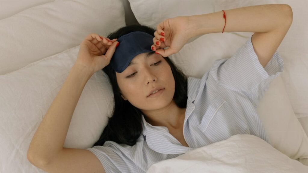 Woman waking up in bed, lifting her sleep mask, embracing morning light.
