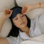 Woman waking up in bed, lifting her sleep mask, embracing morning light.