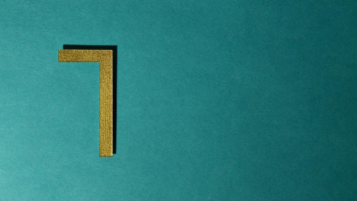 Minimalist image of a golden numeral seven on a teal background, ideal for decorative use.