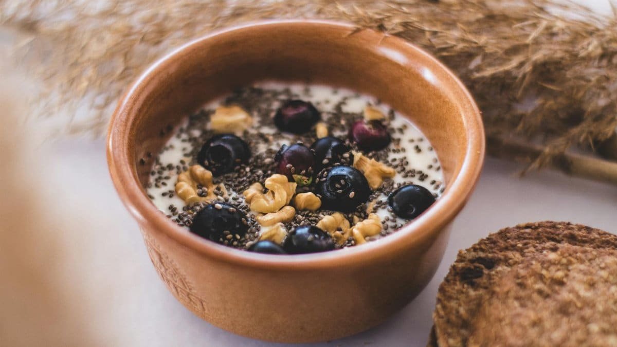 Close-up of a breakfast bowl filled with yogurt, blueberries, chia seeds, and nuts.