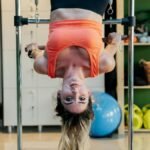 Woman practicing inverted Pilates on a reformer at a gym, focused on fitness and flexibility.