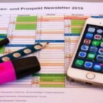 A desk setup featuring a planner, pens, and a smartphone displaying app icons, ideal for productivity.