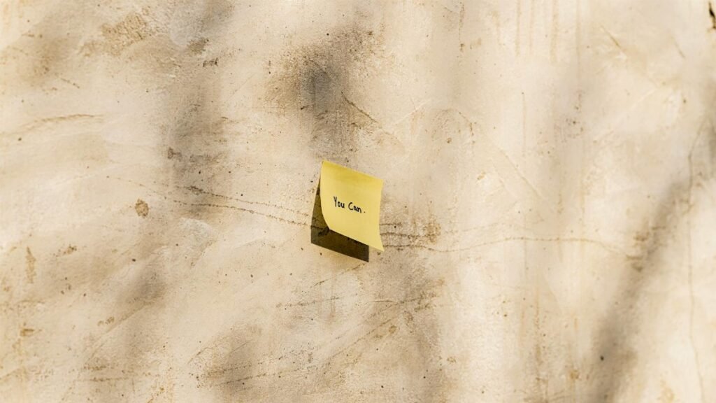A yellow sticky note with 'You Can' written, placed on a textured outdoor wall.