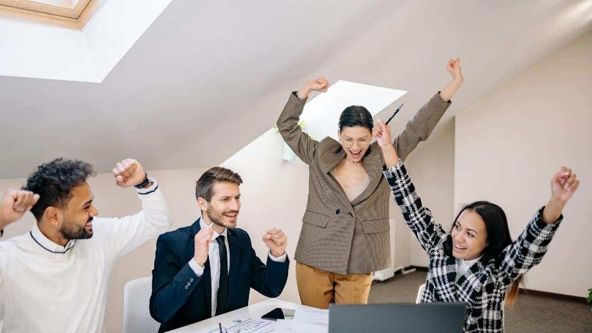 Diverse group of professionals celebrate a team success in a contemporary office setting.