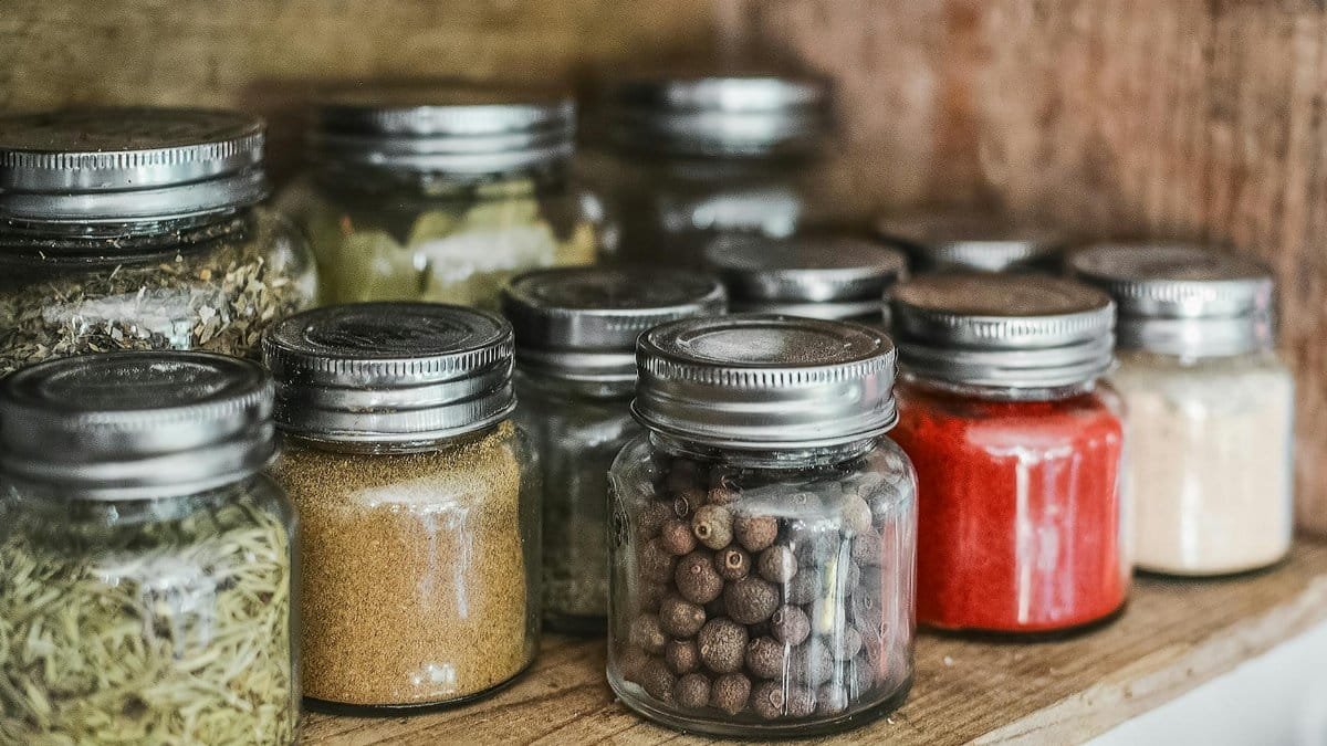 Close-up of assorted spice jars with various herbs on a kitchen shelf, showcasing colorful culinary ingredients.