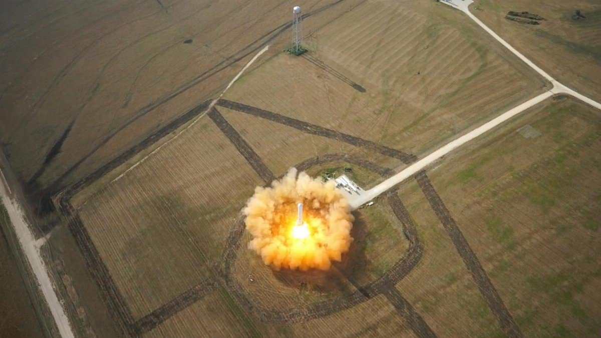 A dramatic aerial shot capturing a rocket's liftoff from a launchpad in open fields.