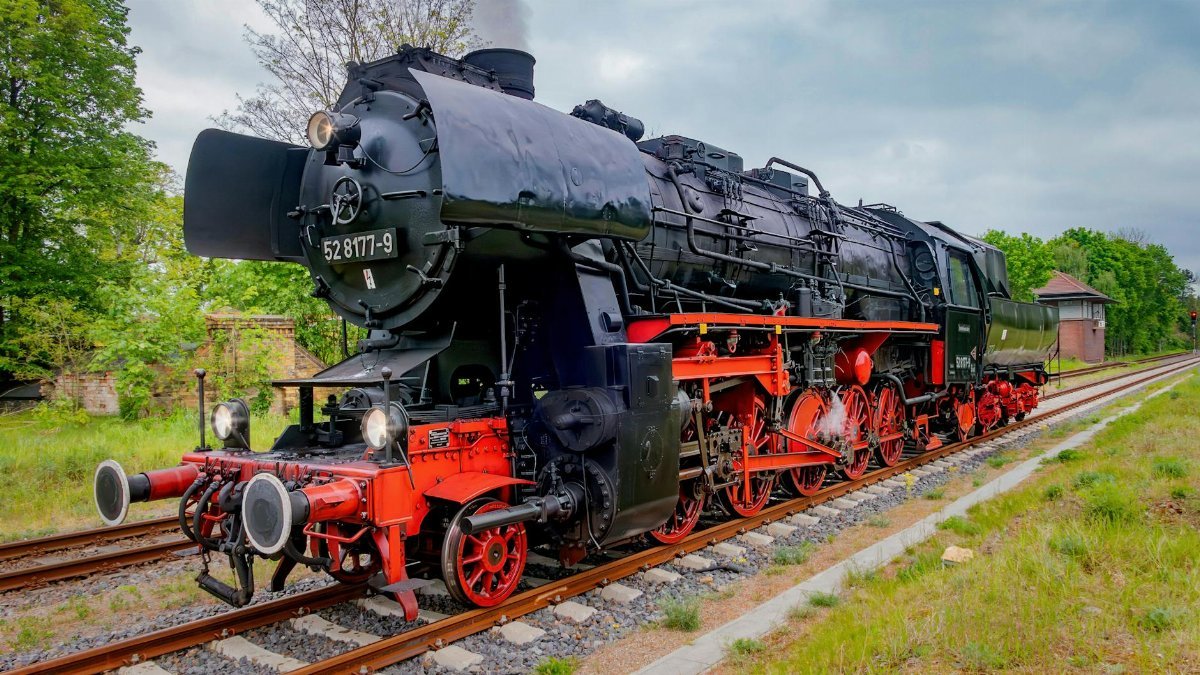 Classic steam locomotive with vibrant red and black colors on railway track</div>