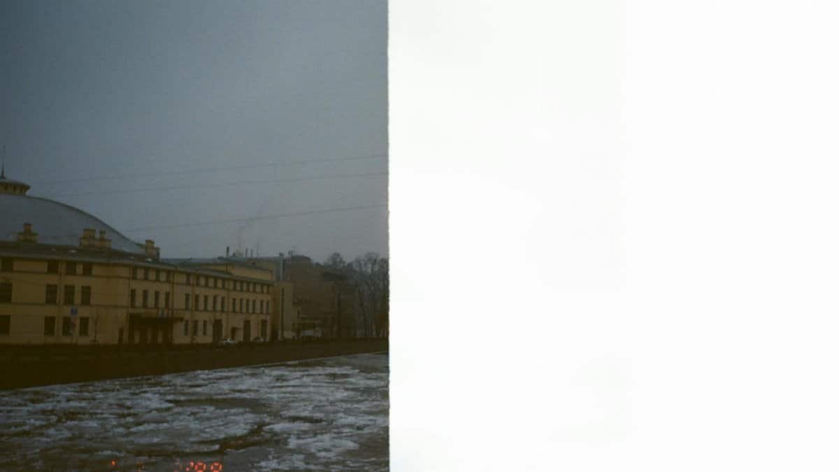 Half-exposed photo of a cityscape in winter showing icy river and buildings.