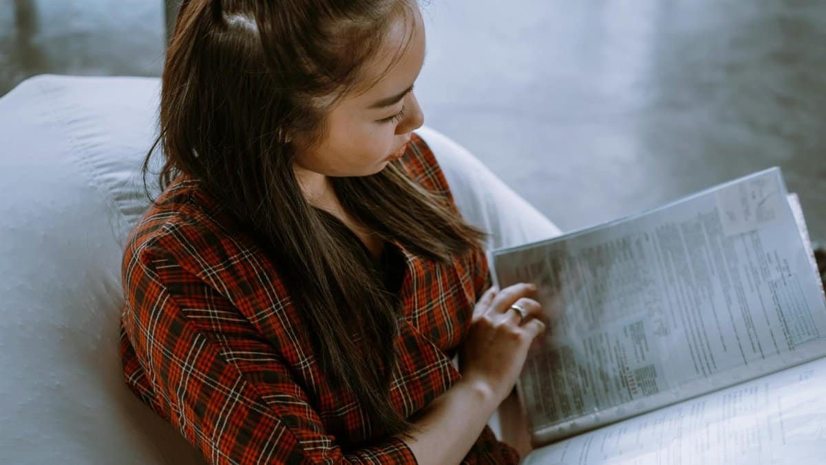 A woman sits indoors reviewing important paperwork, focusing on budgeting and accounting.