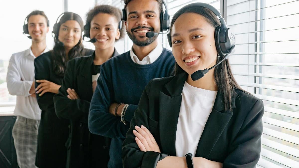 A diverse group of smiling call center agents in an office setting.