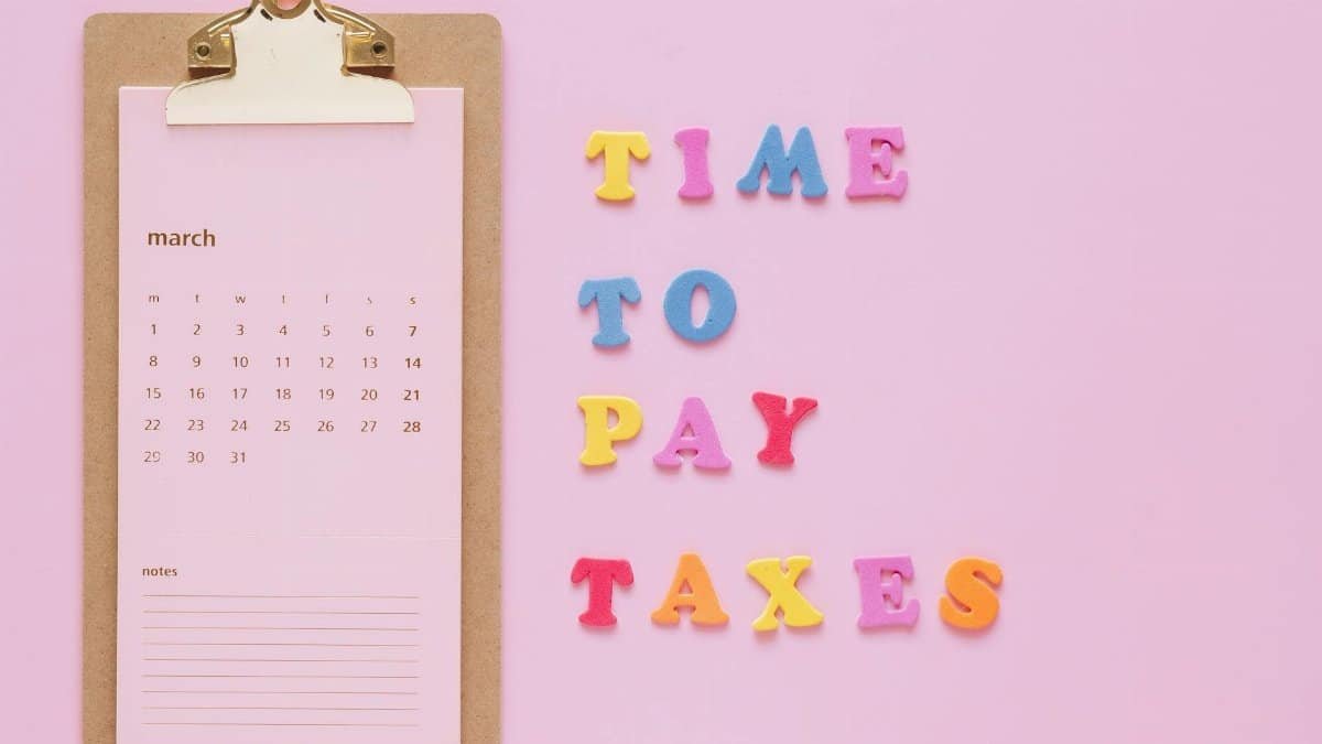 Colorful tax reminder on clipboard against a pink background for March