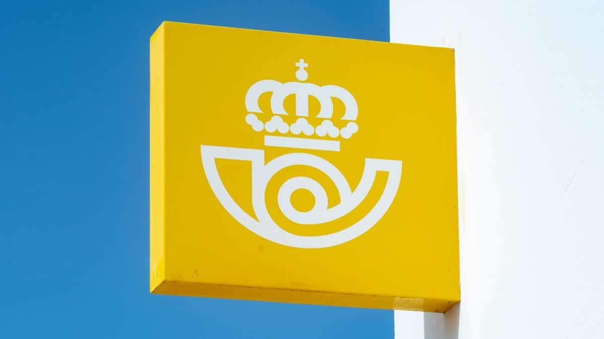 Sign for Spanish postal service against blue sky, capturing iconic symbol.