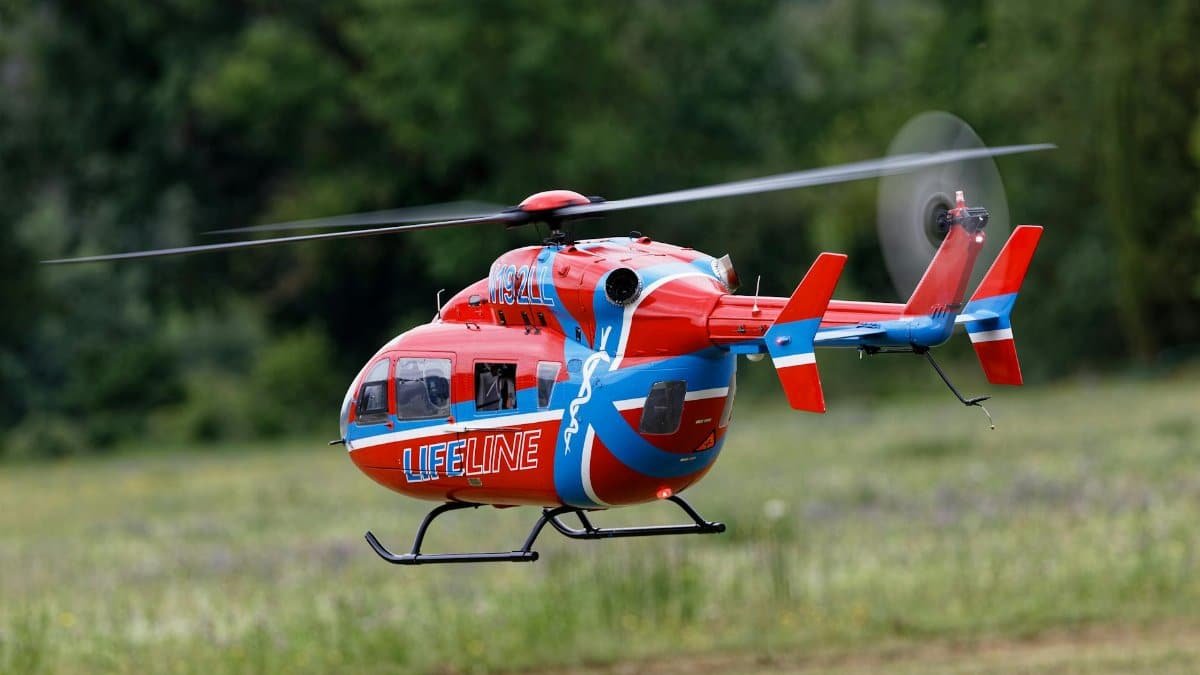 A vivid red and blue Lifeline helicopter flying over a green field, showcasing aviation technology.