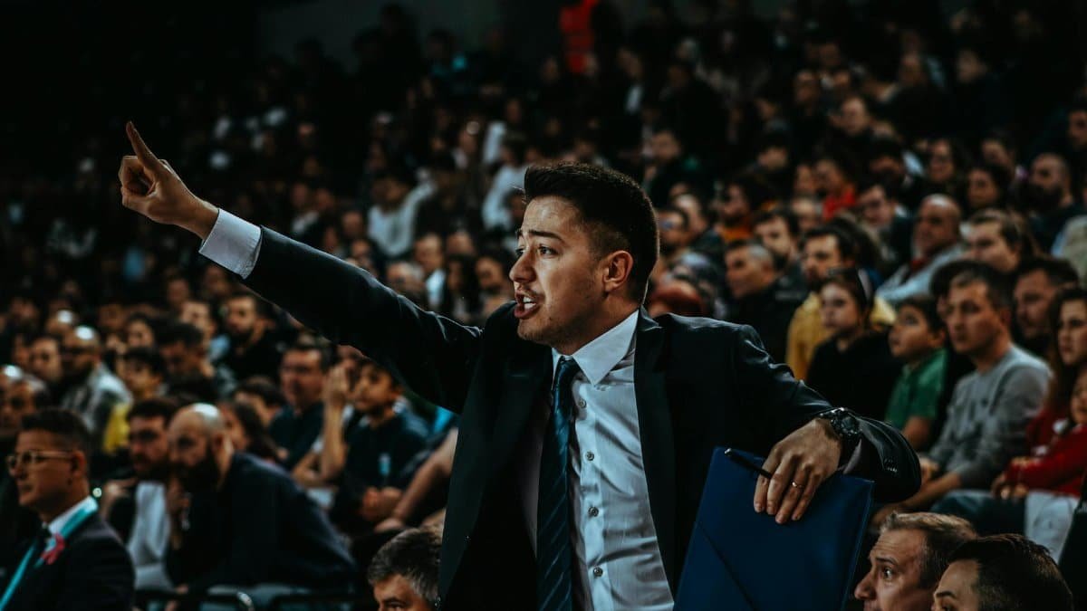 Motivated coach directing during a tense basketball game in a crowded arena.