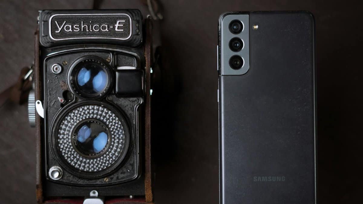 A vintage Yashica camera next to a modern smartphone, showcasing old and new technology.
