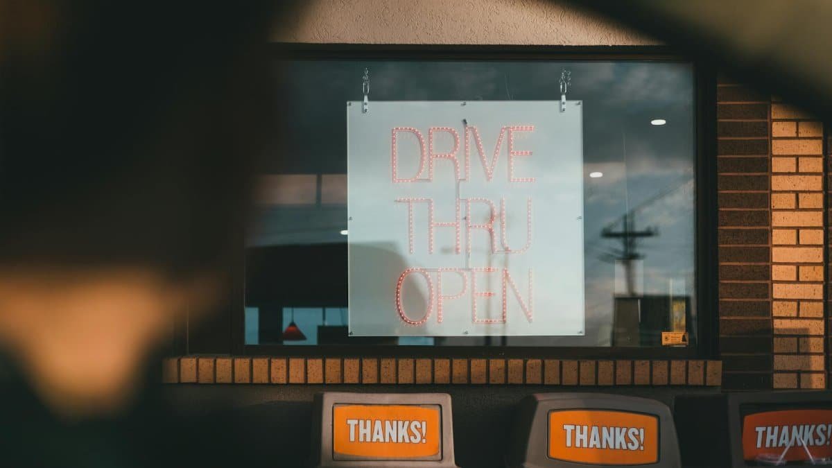 Drive thru service window with open sign at a fast food location. Daytime setting.