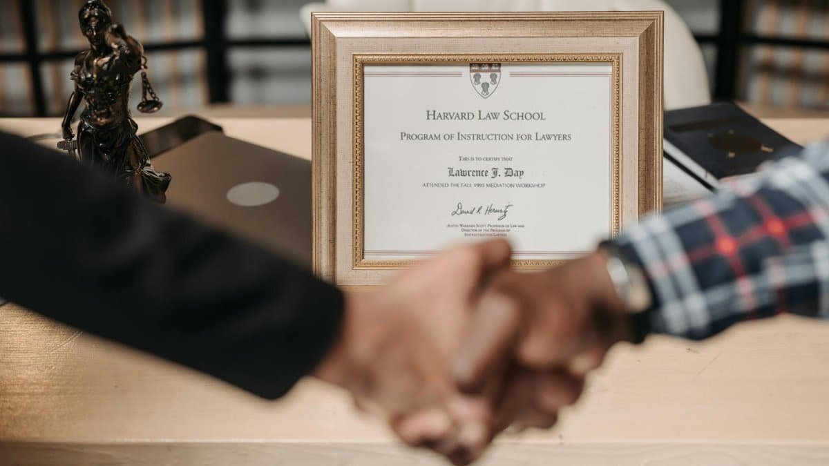 Harvard Law School degree with handshake representing achievement and professional agreement.