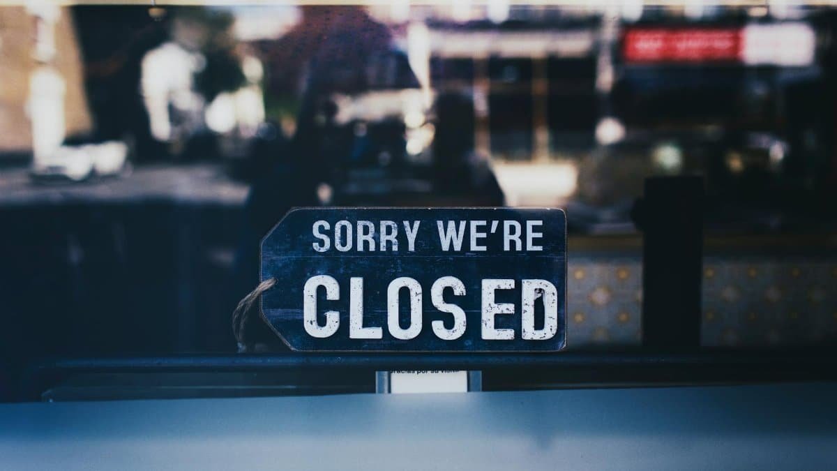 Moody image capturing a 'Sorry We're Closed' sign in a London shop window.