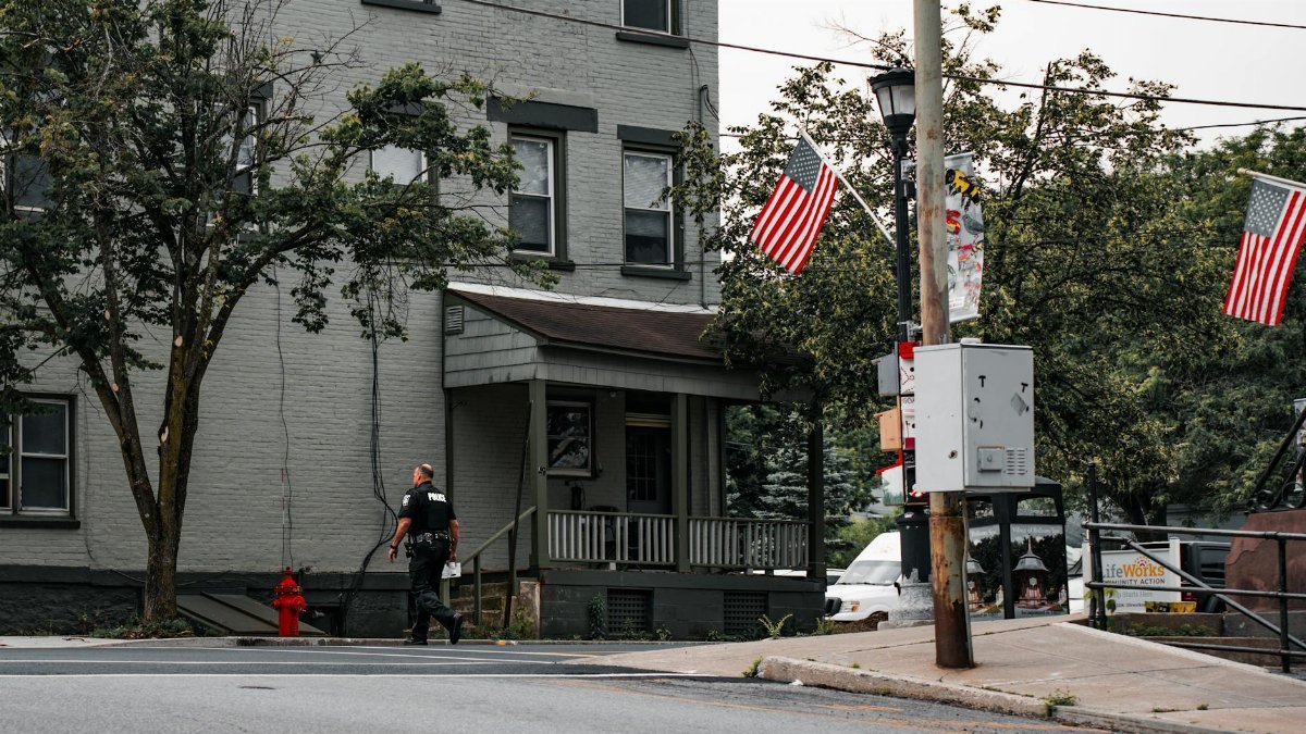 A police officer walks in a small town lined with American flags, representing patriotism.