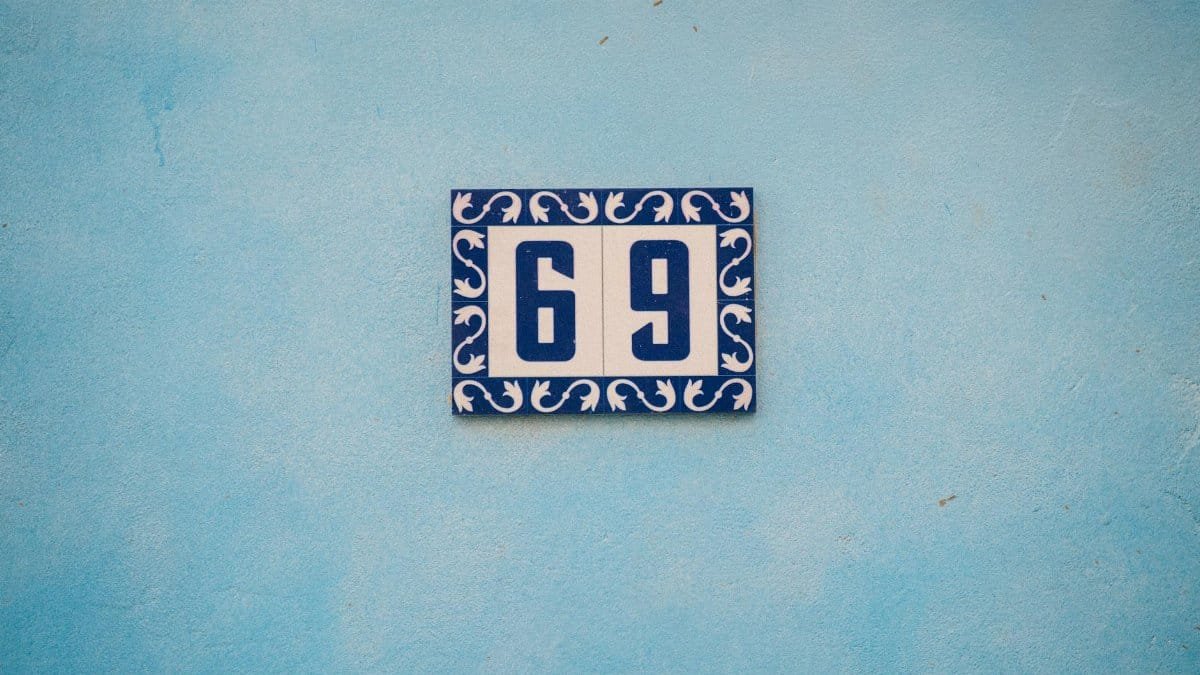 A stylish blue and white house number 69 on a textured blue wall.