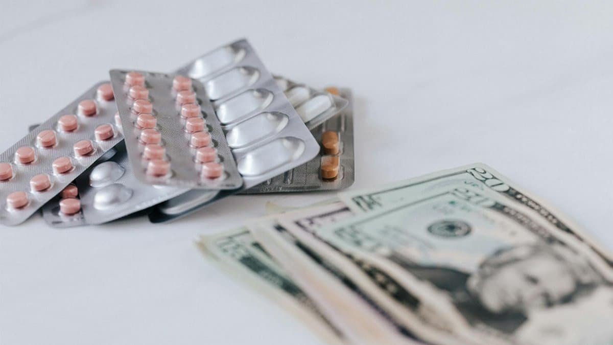 Close-up of medicine blister packs and U.S. currency illustrating healthcare costs.