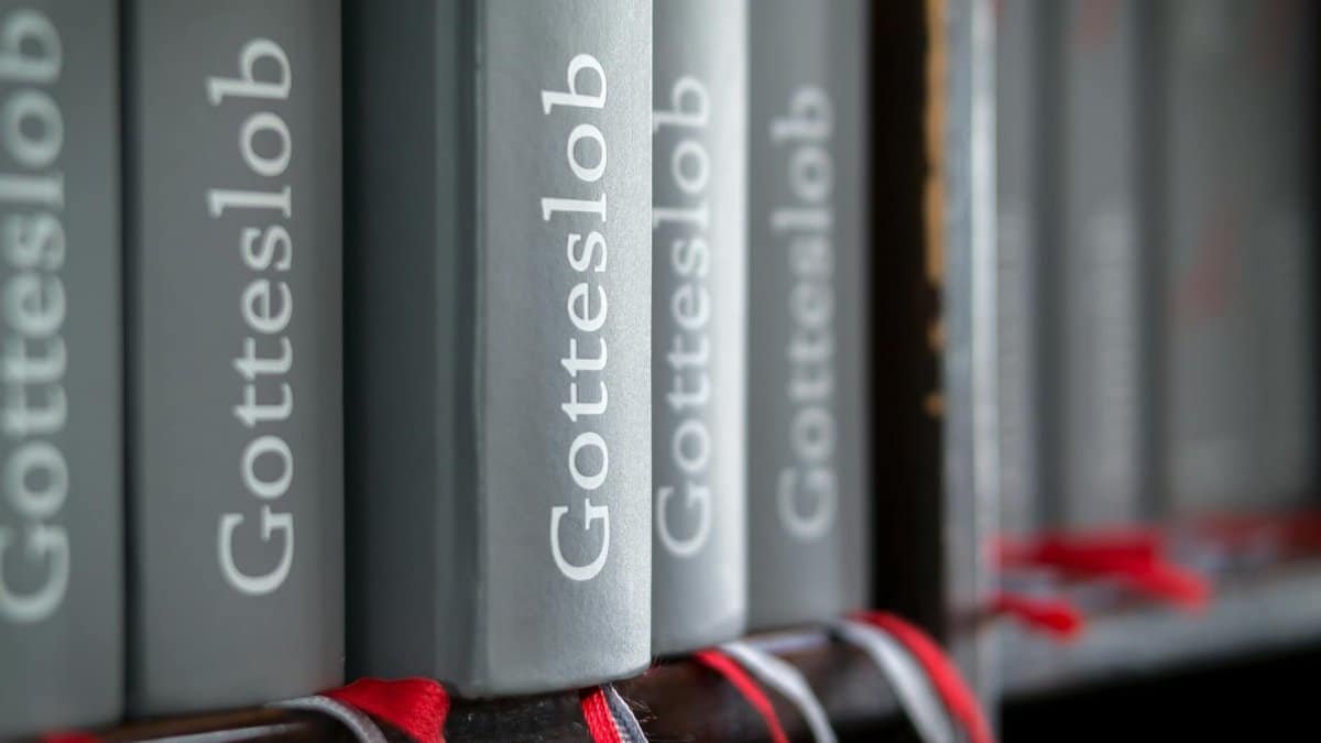 Macro shot of Gotteslob hymn books with red bookmarks neatly arranged on a bookshelf.