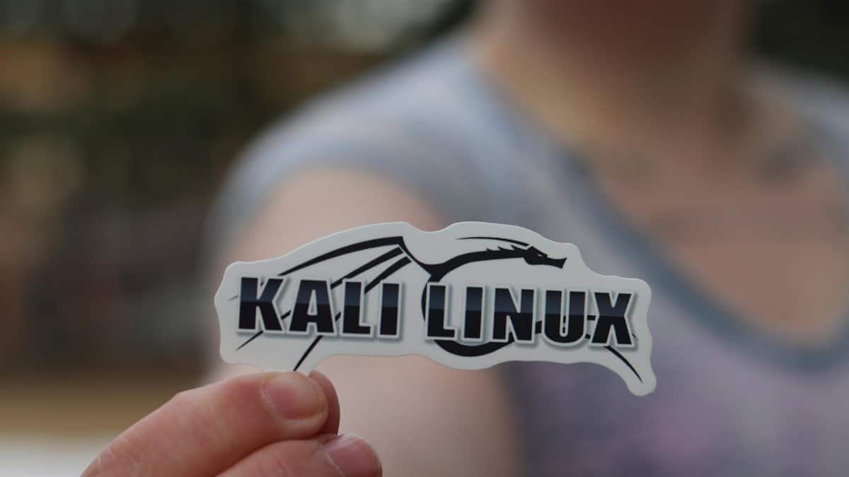 Close-up shot of a person holding a Kali Linux sticker, highlighting cyber security themes.