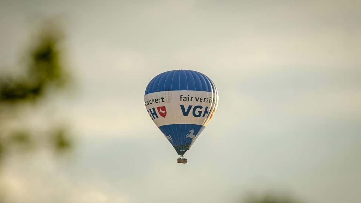 A blue hot air balloon with text flying in a clear sky, creating a serene travel scene.