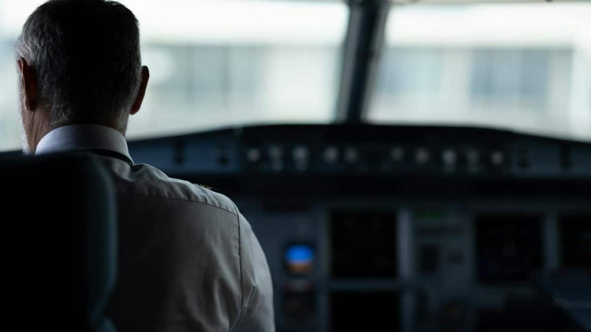 A focused view of an airline pilot in the cockpit, emphasizing responsibility and aviation control.