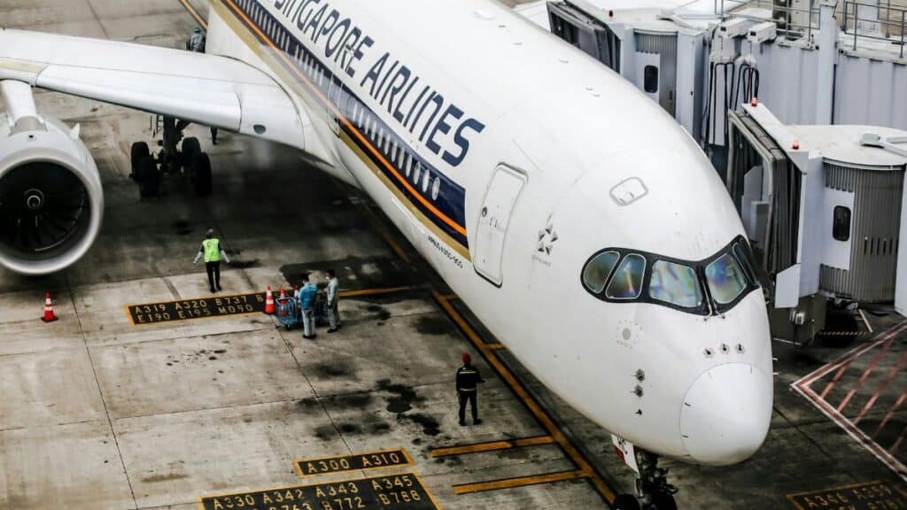 Singapore Airlines Airbus A350 at the gate, with ground crew and jet bridge.