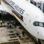 Singapore Airlines Airbus A350 at the gate, with ground crew and jet bridge.