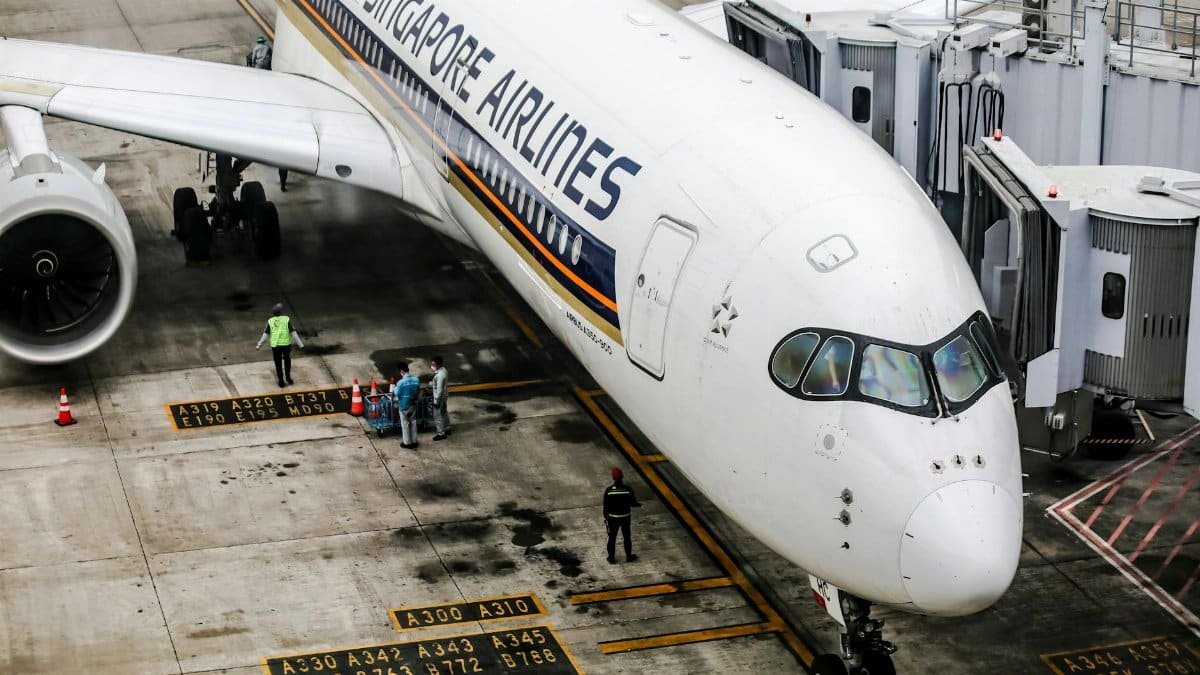 Singapore Airlines Airbus A350 at the gate, with ground crew and jet bridge.