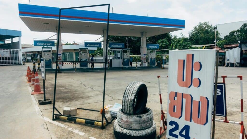 A modern fuel station featuring gas pumps and a tire repair service sign in an urban setting.