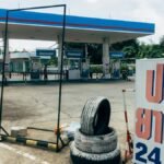 A modern fuel station featuring gas pumps and a tire repair service sign in an urban setting.