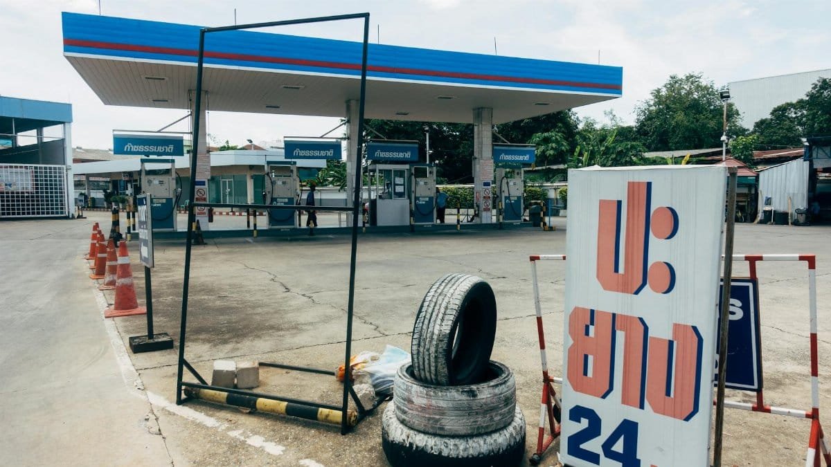 A modern fuel station featuring gas pumps and a tire repair service sign in an urban setting.