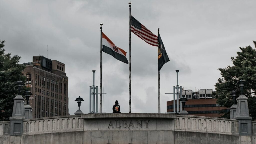 Three flags flying above a stone monument in downtown Albany, New York.