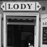 Black and white image of a classic ice cream shop in Gdańsk, Poland, featuring vintage signage.