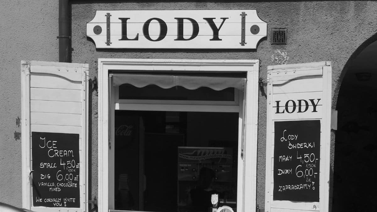Black and white image of a classic ice cream shop in Gdańsk, Poland, featuring vintage signage.