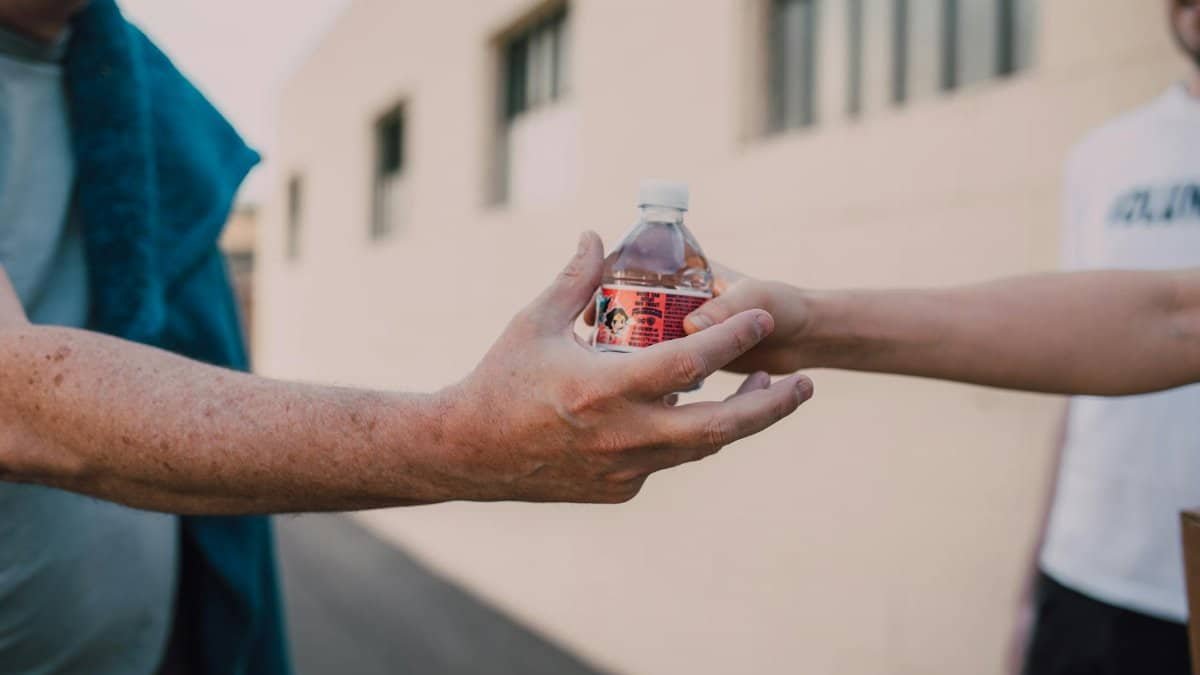 Two people exchanging a bottle outdoors, emphasizing connection and kindness.