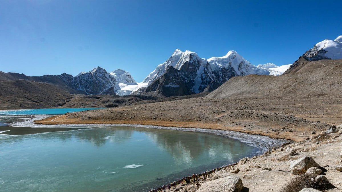 Experience the breathtaking landscape of Yumthang, SK, India with snowcapped peaks and clear reflections.