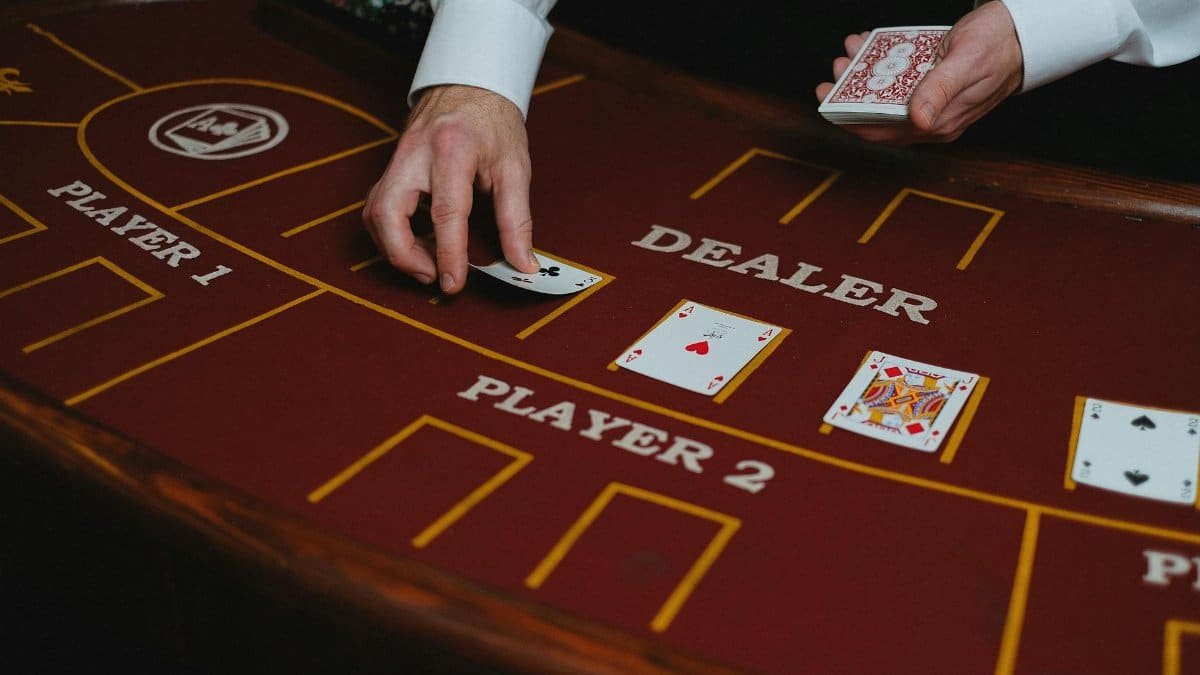 A casino dealer distributes playing cards at a poker table, ready for a game.