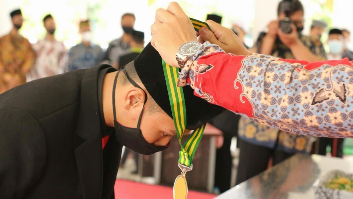 A young man receives a medal during a graduation ceremony.