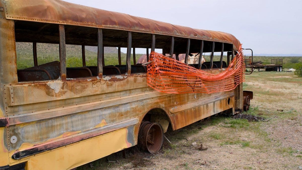 Explore a rusting, abandoned school bus in the Arizona desert, embodying decay and urban exploration.