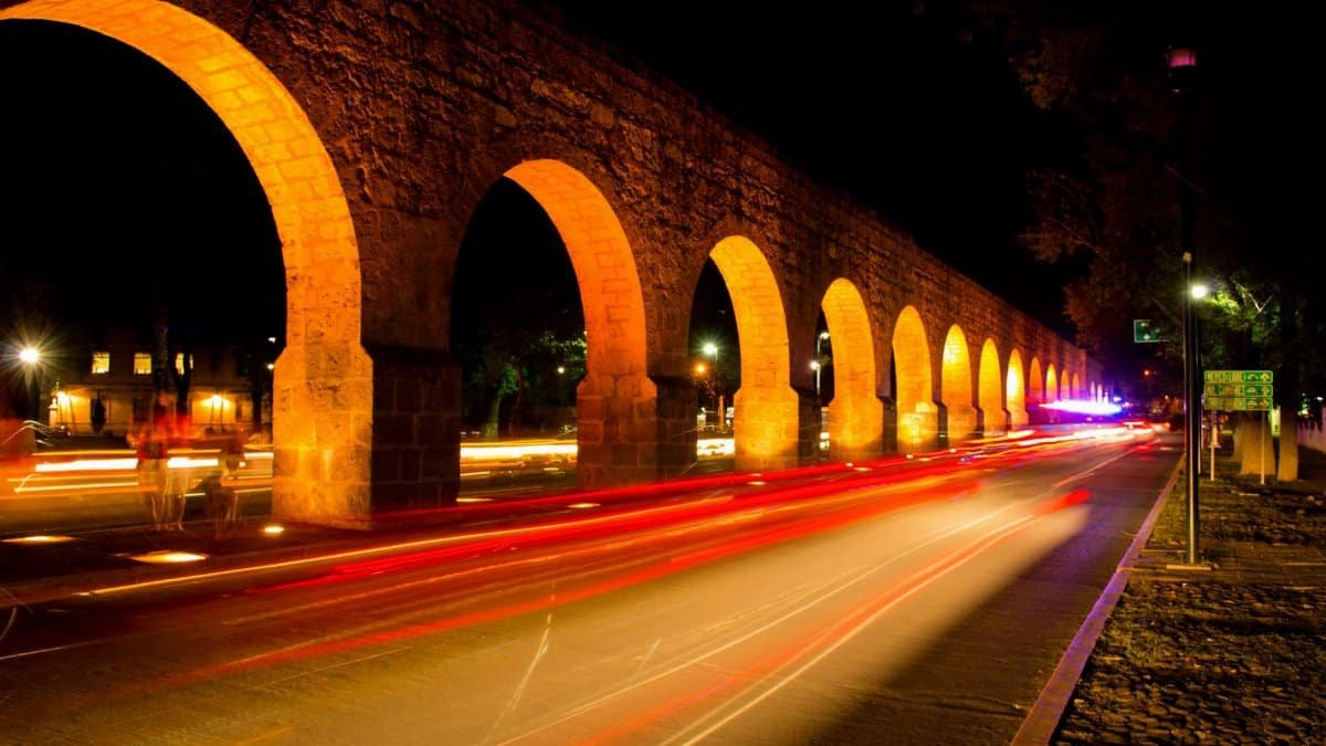 Nighttime long exposure of Morelia's historic aqueduct with illuminated arches.