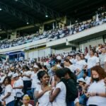 A vibrant crowd gathers in a stadium, enjoying an exciting event under a covered roof.