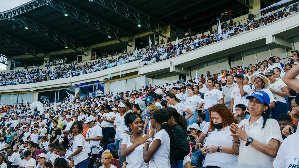 A vibrant crowd gathers in a stadium, enjoying an exciting event under a covered roof.