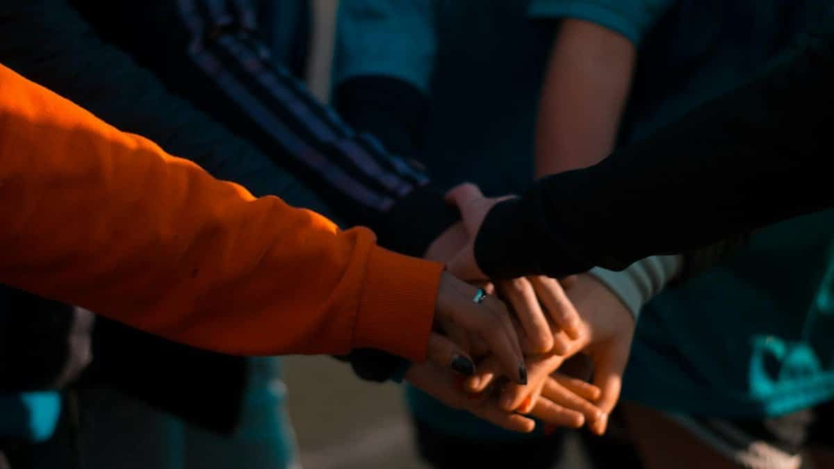 A close-up of diverse hands stacked together outdoors, symbolizing teamwork and unity.