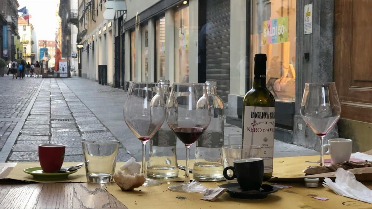 Empty wine glasses on a street-side table in Turin, Italy, create a charming urban ambiance.