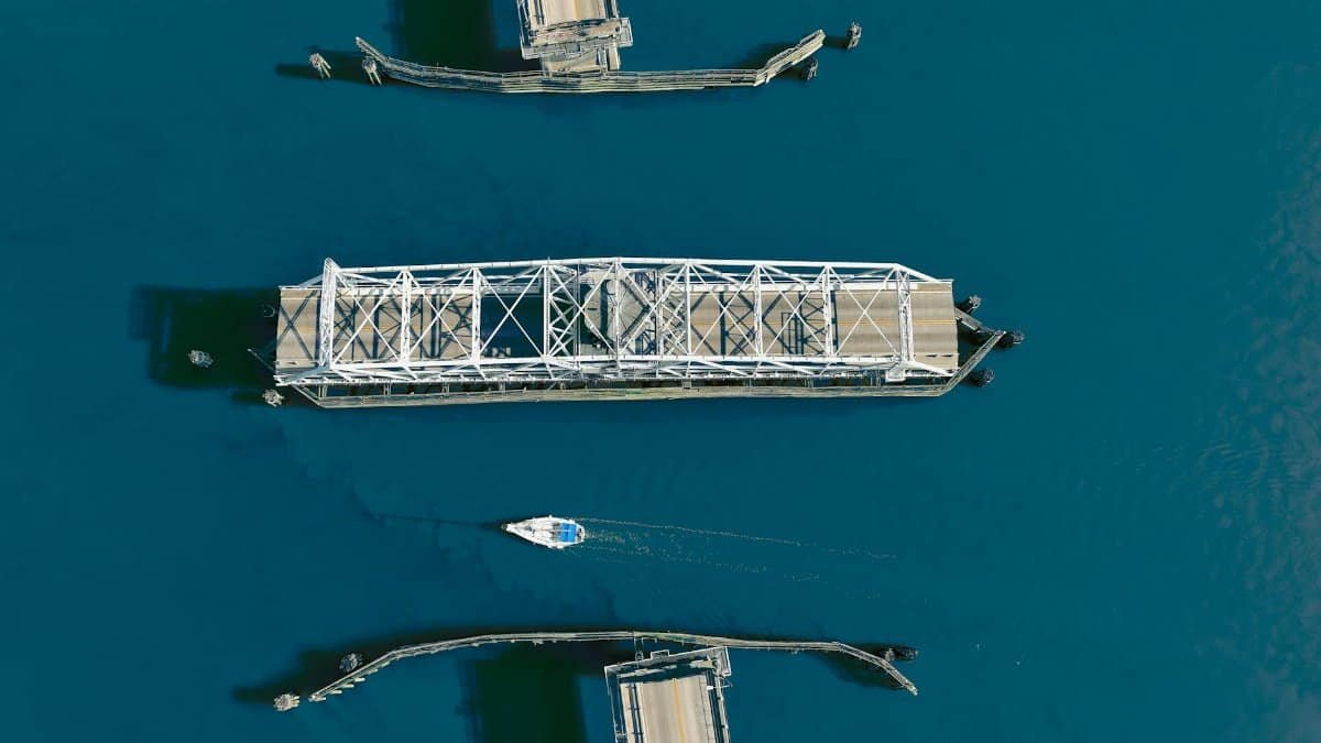 Aerial shot of a swing bridge opening over a strait with a sailing boat below, located in Beaufort, SC.